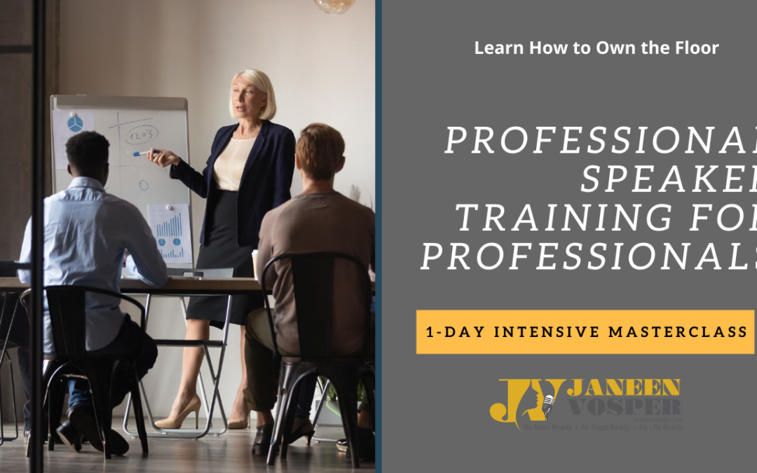 A londe business woman in a suit conducting public speaking training with a few office workers sitting around a table. A white board or flip chart is in the backgrou. The words say Learn How to speak to the room Professional Speaker Training - 1-Day Intensive